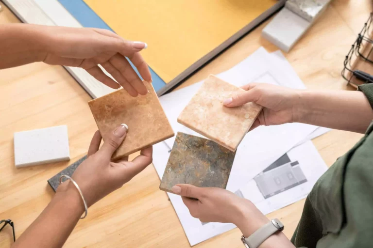 Hands Of Two Young Female Designers Comparing Samples Of Marble Tiles